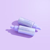 Two bottles of facial oil with droppers displayed on a lilac background.