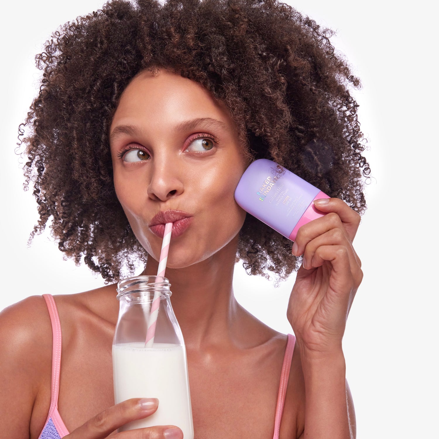Woman drinking from a Milk Jar and a bottle of CabanaMilk against her cheek with a white background