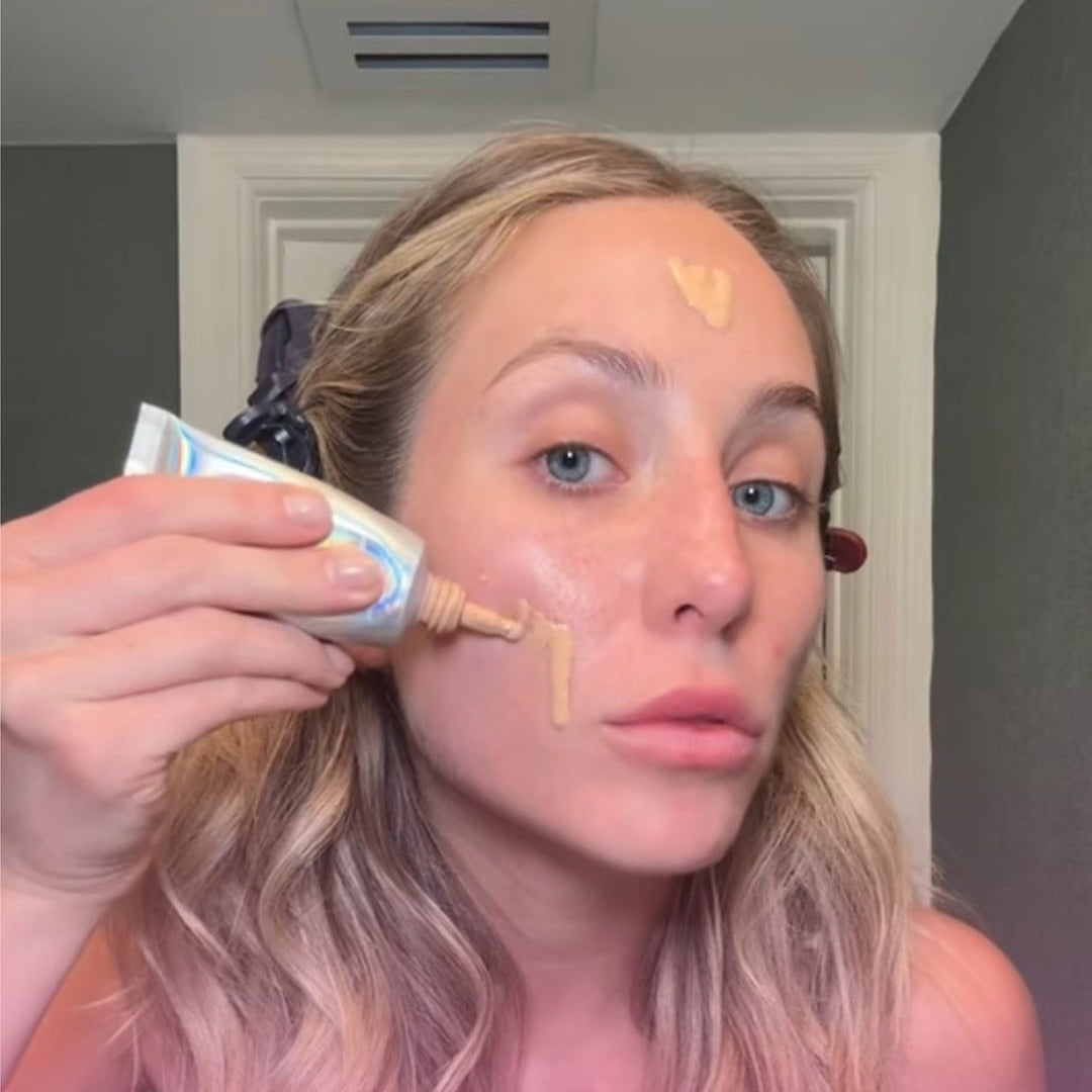 Alix Earle applying BeautyScreen foundation to their face with a tube labeled 'Shade 2.5'.