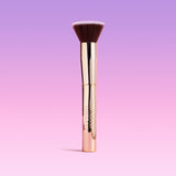 Makeup brush with gold handle on a gradient purple background