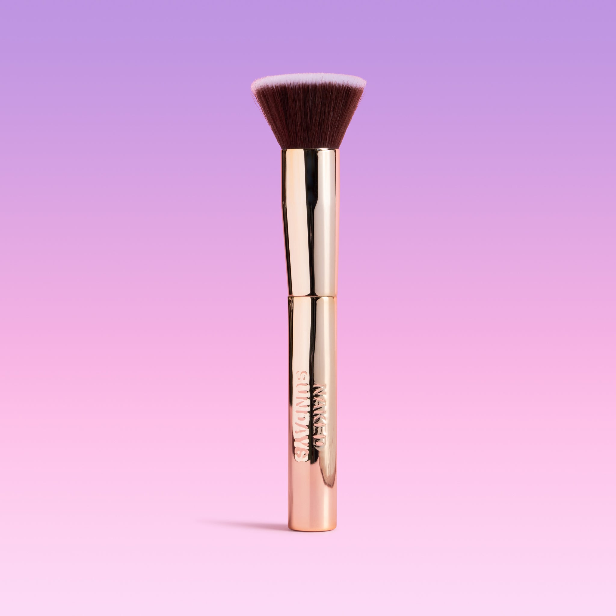 Makeup brush with gold handle on a gradient purple background