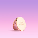 Gold Compact mirror with 'Naked Sundays' branding on a pink gradient background