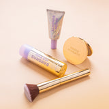 SPF Makeup products including BeautyScreen, CabanaClear in Illuminating, a gold compact mirror, and a gold brush with 'Naked Sundays' branding on a beige background.
