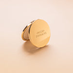 Gold Compact mirror with 'Naked Sundays' branding on a beige background