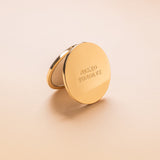 Gold Compact mirror with 'Naked Sundays' branding on a beige background