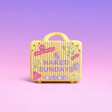 A small yellow ribbed suitcase with a handle, decorated with colorful travel-style stickers and the words 'NAKED SUNDAYS' on the front, set against a soft pink-to-purple gradient background.